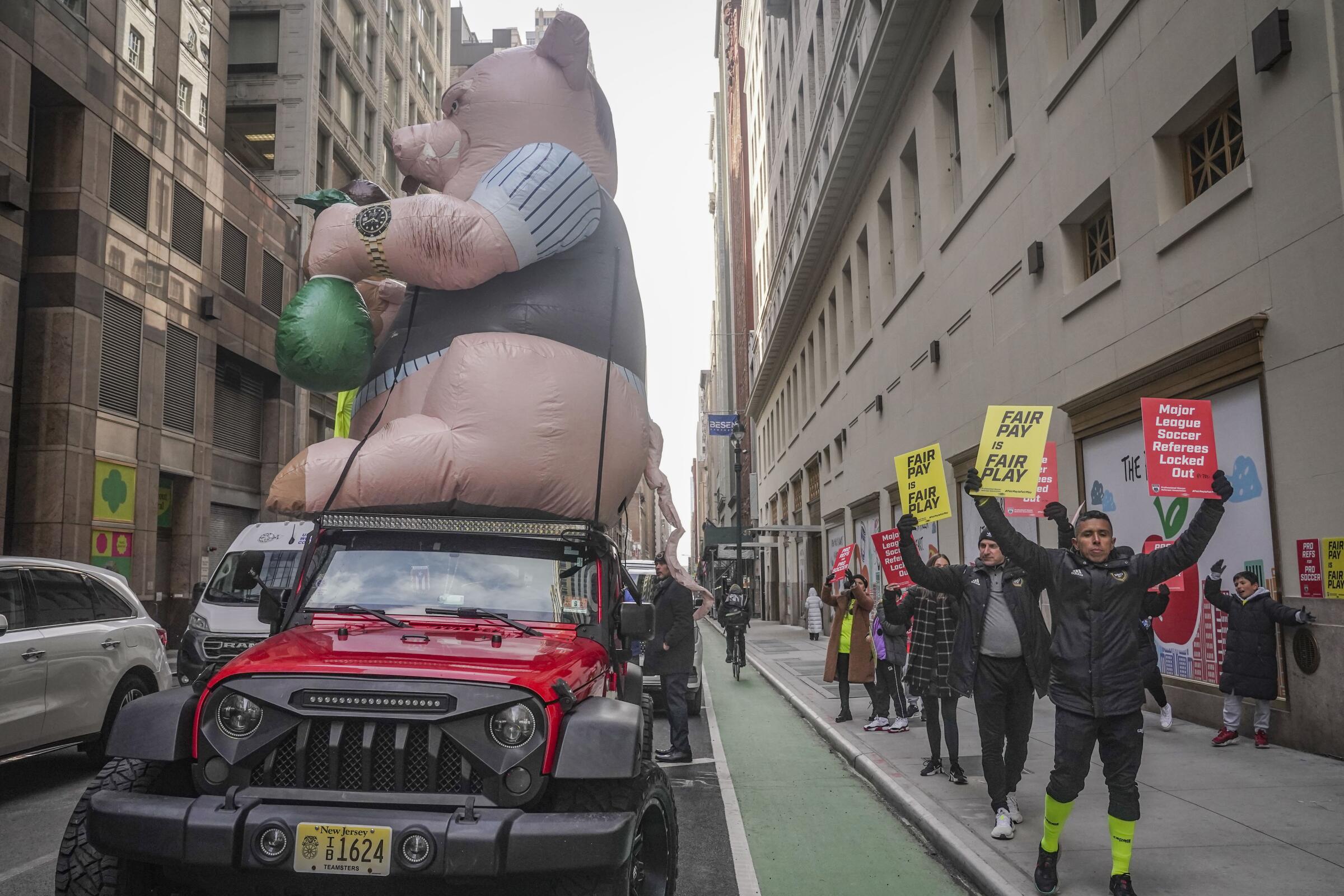 MLS referees and supporters picket outside MLS headquarters in New York around a "Greedy Pig" balloon on Feb. 21.