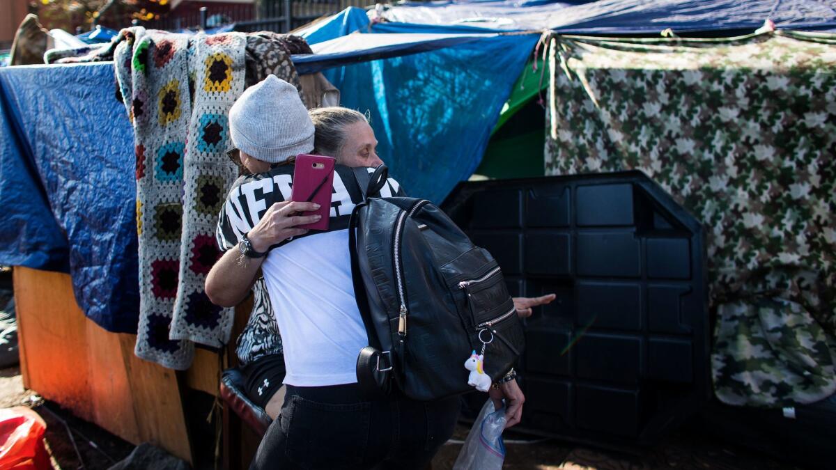 Lisa Bell, 51, right, gets a hug from a friend who stopped by to visit her at the homeless encampment next to the Santa Ana River where she's been living for four months.