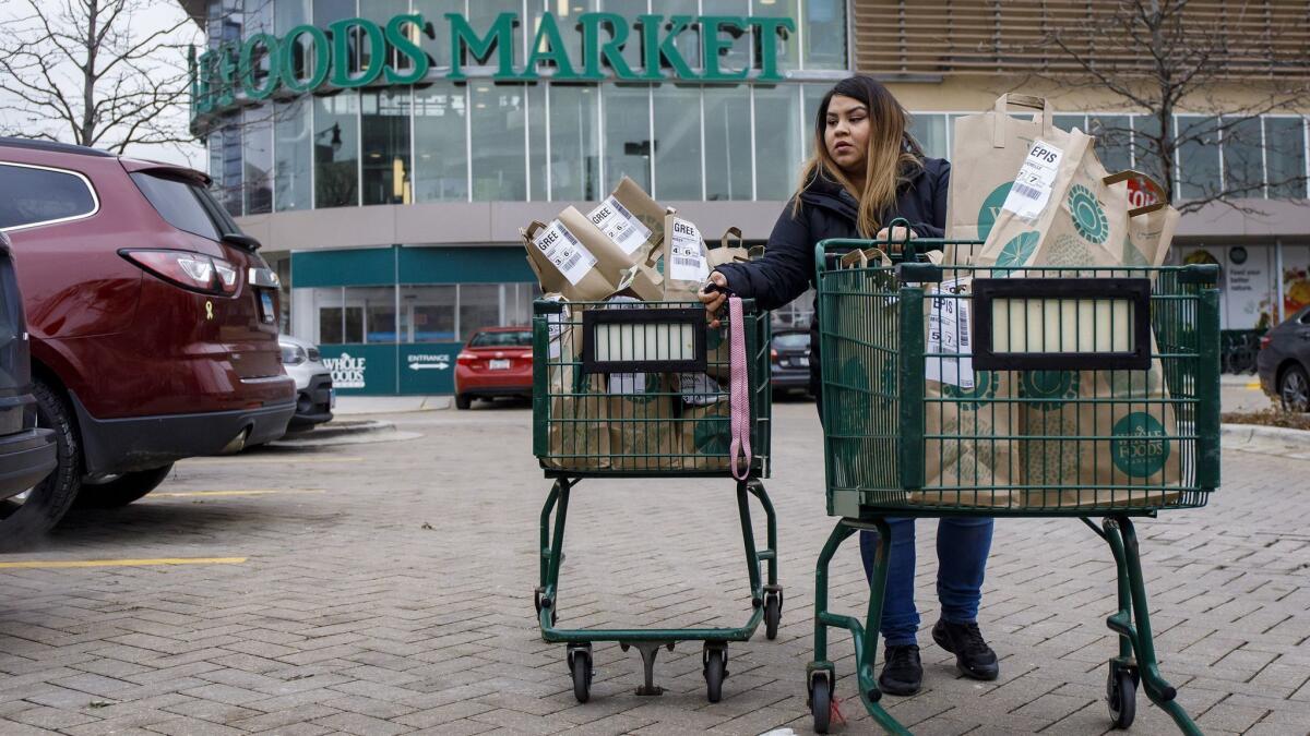 Alid Alvarado transports orders for three different Instacart customers to her car at a Whole Foods store in the Chicago area.