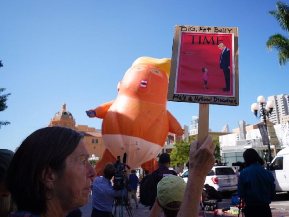Anti-Trump protesters with a sign and a Baby Trump balloon 