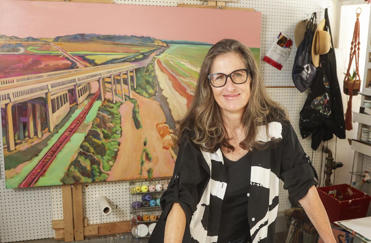 Artist Kate Joiner, standing with one of her paintings of the Torrey Pines area