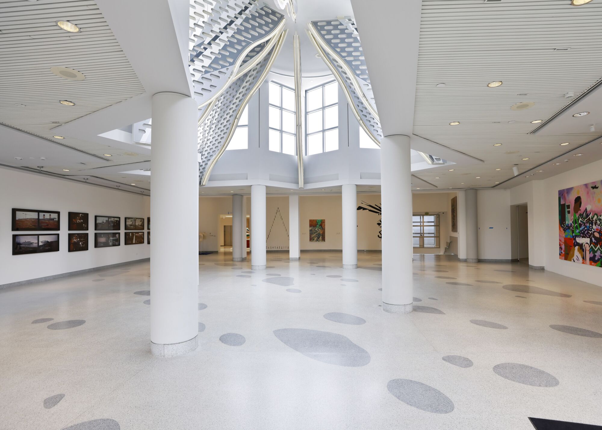A light-filled atrium with paintings on the walls 