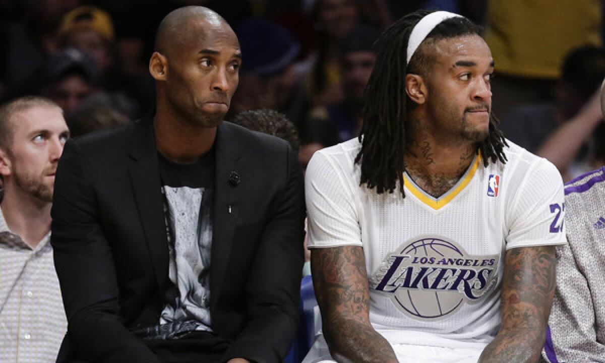 Injured Lakers star Kobe Bryant, left, and teammate Jordan Hill watch from the bench during the Lakers' Christmas Day loss to the Miami Heat at Staples Center. The Lakers' struggles have been reflected in television ratings for their games.