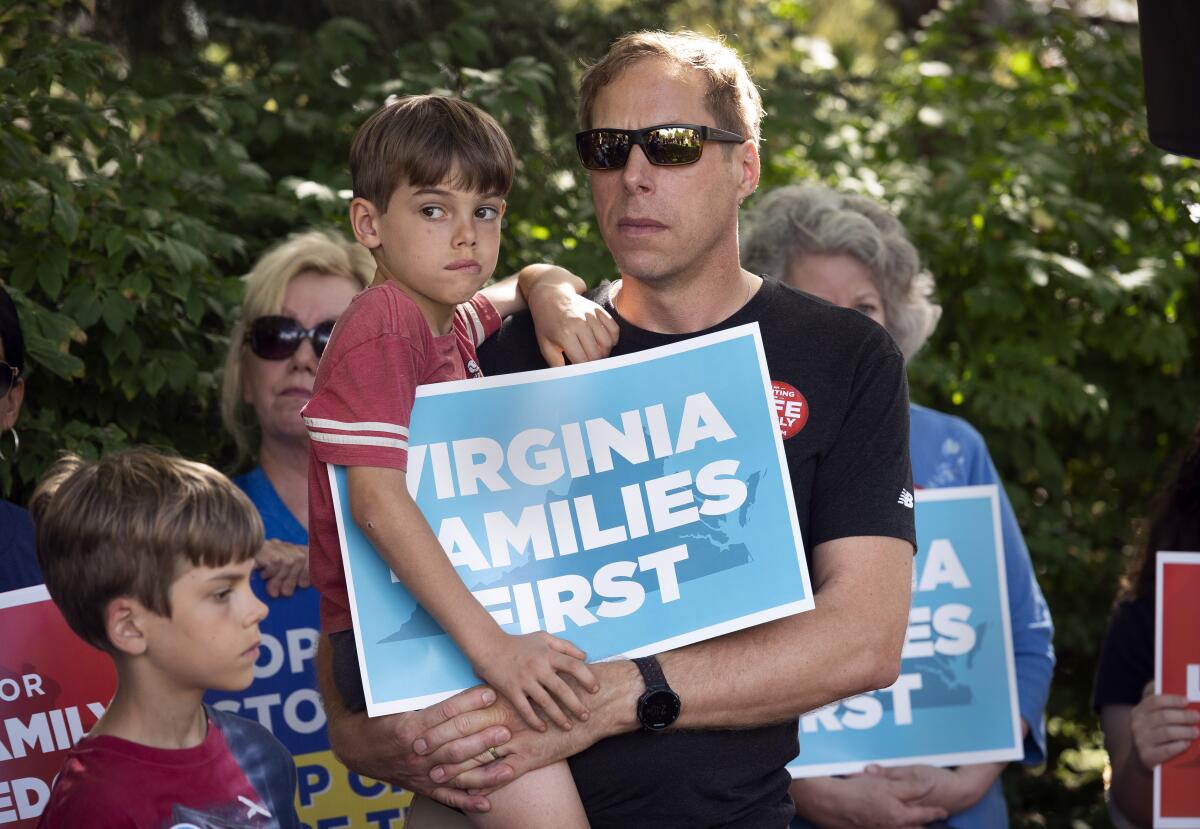 A man and his young child hold a placard that says "Virginia families first."