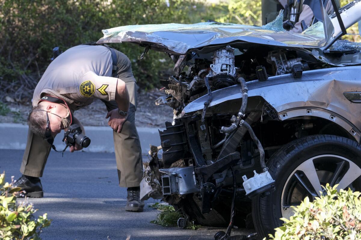 A Los Angeles County Sheriff's deputy examines a damaged vehicle after a crash involving Tiger Woods on Feb. 23.