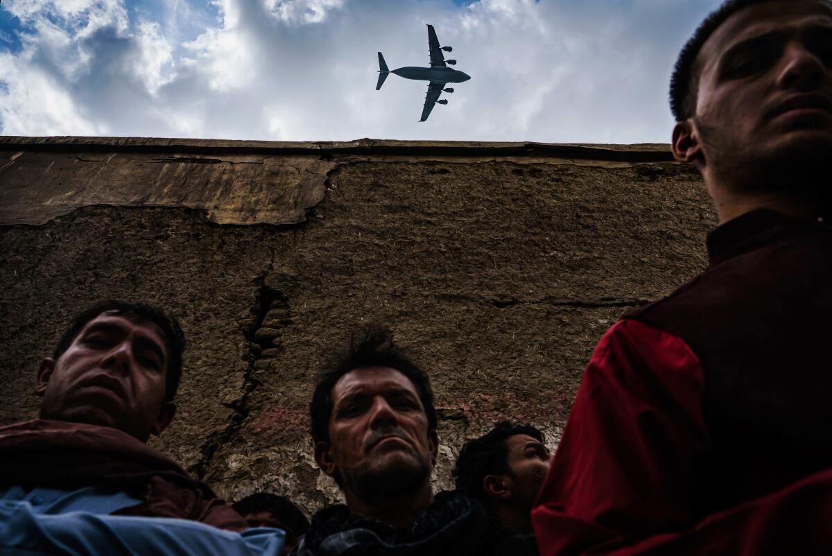 A military transport plane flies over relatives and neighbors of the Ahmadi family