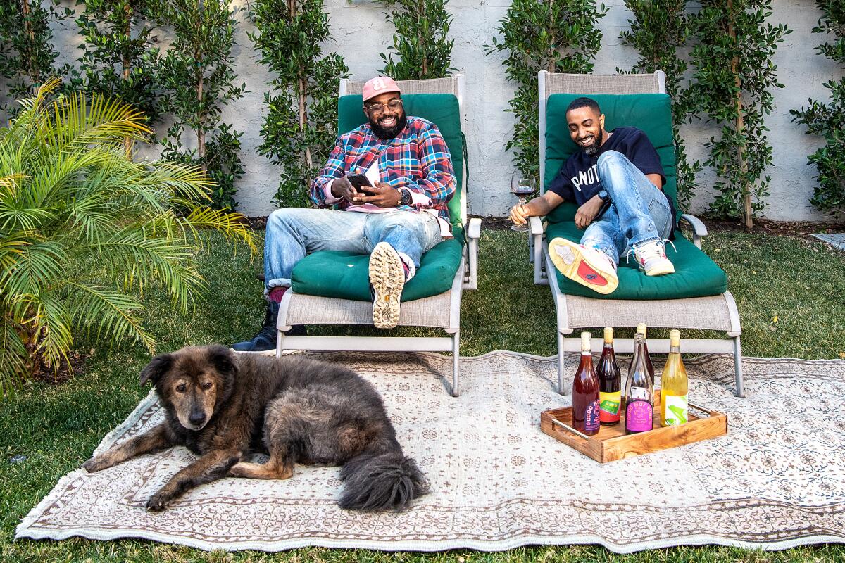 Teron Stevenson, left, and Khalil Kinsey, two of the cofounders of Natural Action Wine Club, on lounge chairs with a dog.
