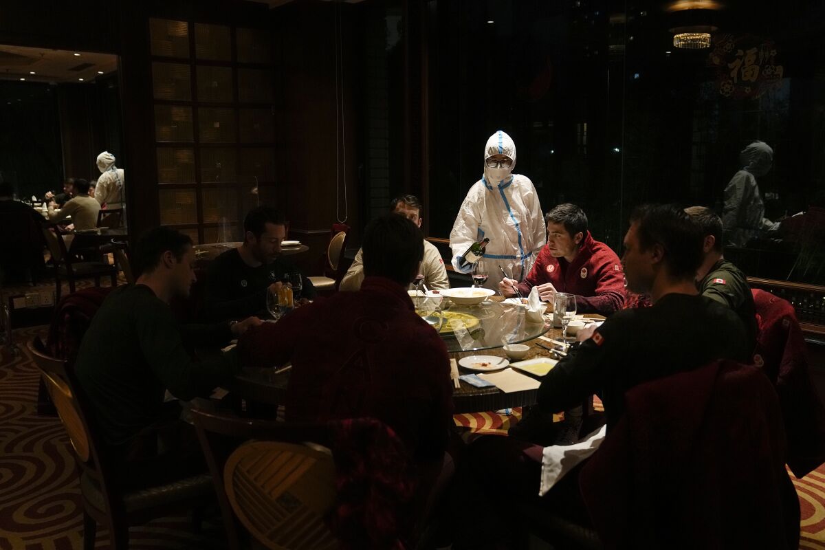 A waitress serves a table in protective gear in a restaurant inside the Shangri-La Hotel at the 2022 Winter Olympics, Wednesday, Feb. 16, 2022, in Beijing. (AP Photo/Jae C. Hong)