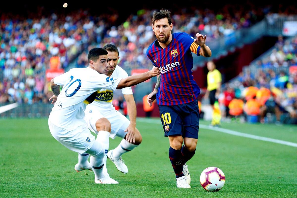 El delantero argentino del Barcelona Lionel Messi (d) pelea un balón con el defensa de Boca Juniors Lucas Olaza durante el trofeo Joan Gamper, esta tarde en el Nou Camp.