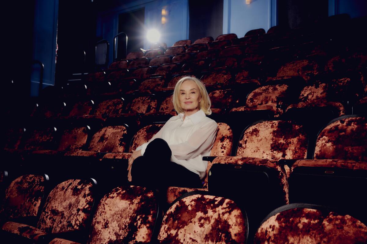 Jessica Lange sits amid the empty red velvet seats of a theater.