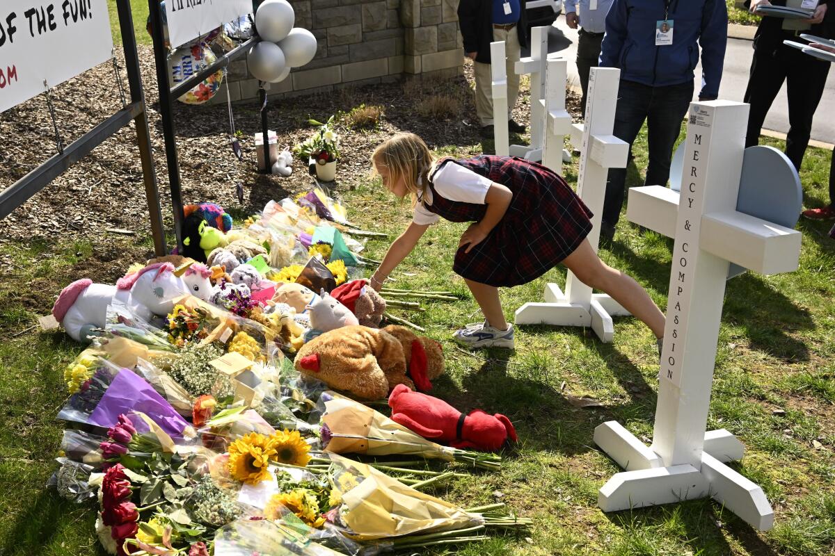 Una niña coloca una ofrenda en un monumento improvisado por las víctimas de un tiroteo