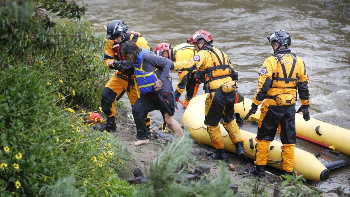 Members of the San Diego Fire Rescue Lifeguards assist a woman out of a raft after she went into Chollas Creek behind Charles Lewis III Memorial Park on Home Avenue.