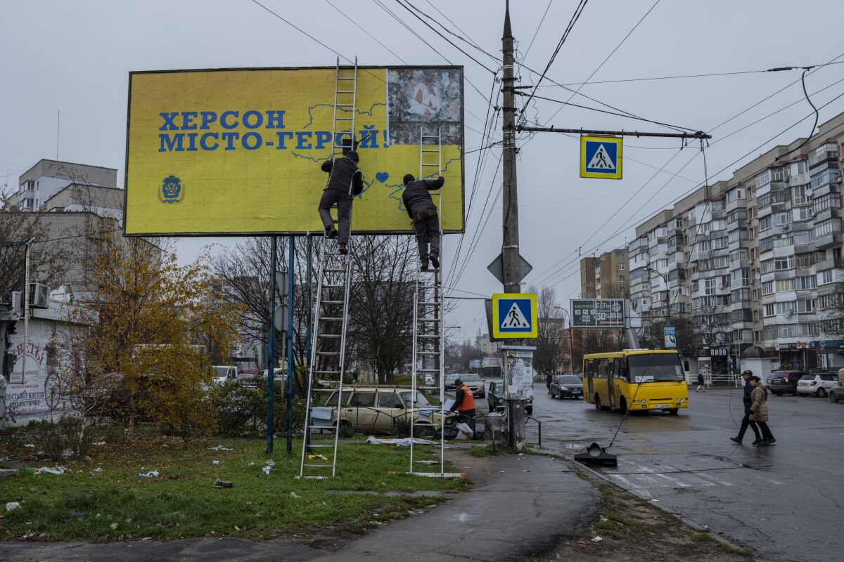 City workers set up a billboard in Kherson, southern Ukraine, Thursday, Nov. 24, 2022. The billboard reads in Ukrainian "Kherson Hero City". (AP Photo/Bernat Armangue)