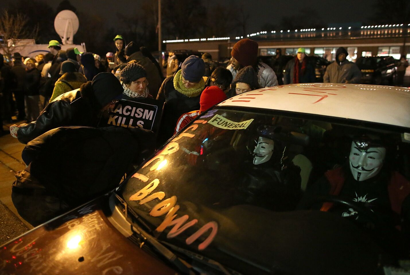 Demonstrators listen to a car radio as a grand jury's decision is delivered in front of the Ferguson Police Department.
