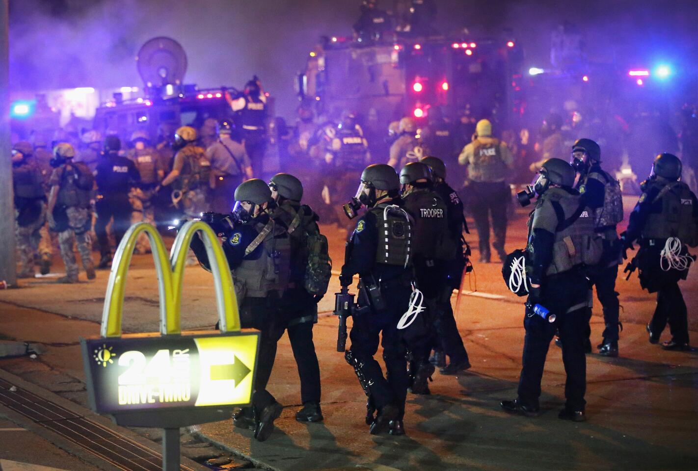 Police advance through a cloud of tear gas toward demonstrators protesting the killing of 18-year-old Michael Brown in Ferguson, Mo.