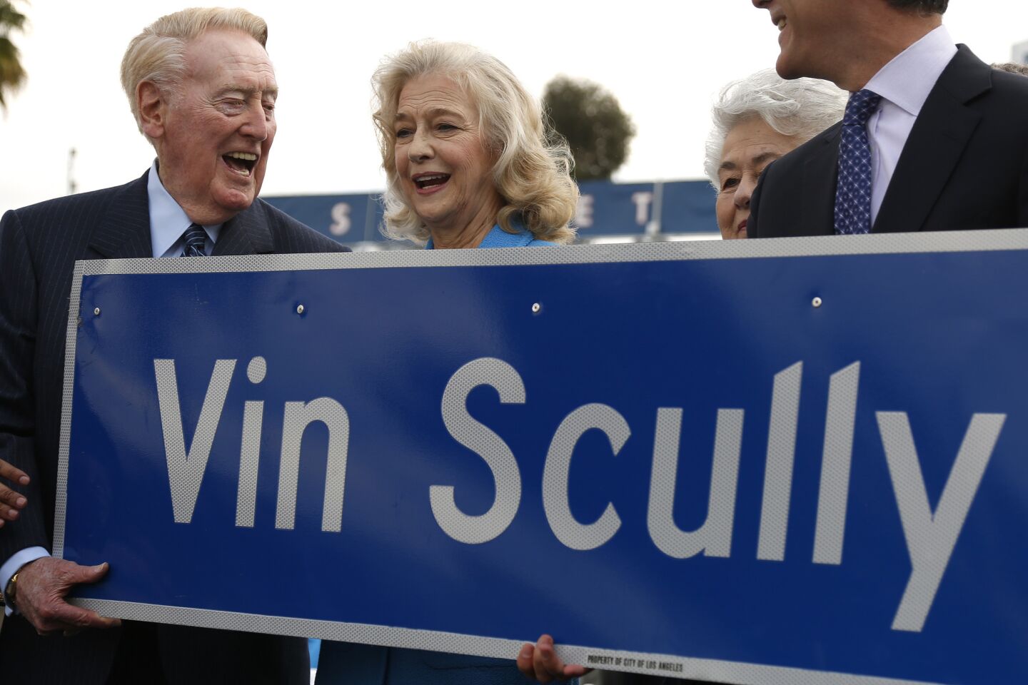Vin Scully and his wife, Sandra Hunt, help hold a new Vin Scully Avenue sign during a ceremony renaming a street leading into Dodger Stadium.
