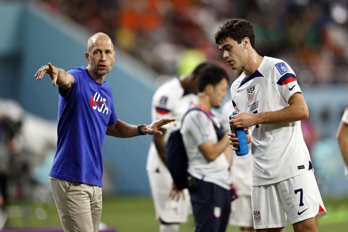 U.S. coach Gregg Berhalter points down the pitch while speaking to Gio Reyna during the 2022 World Cup. 