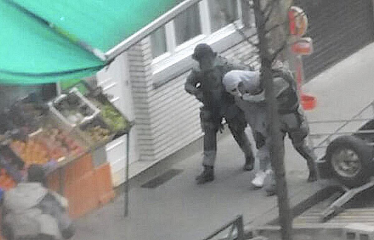 Police detain a man in Brussels' Molenbeek district on March 19 who is believed to be connected to a suspect in the Paris attacks. Residents say the district shouldn't be demonized for the actions of a few.