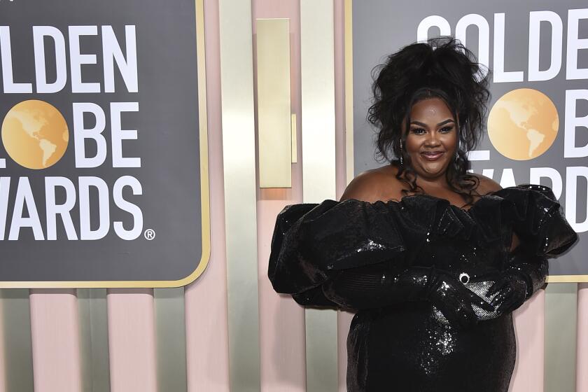 Nicole Byer in a black dress on the gray carpet at the Golden Globe Awards 