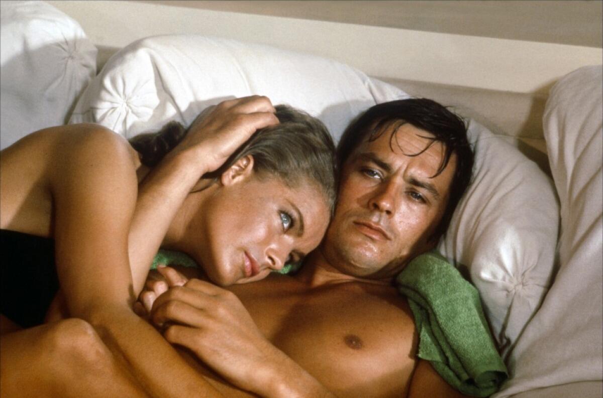 Romy Schneider and Alain Delon, nude from the waist up, lie in bed in "La Piscine"