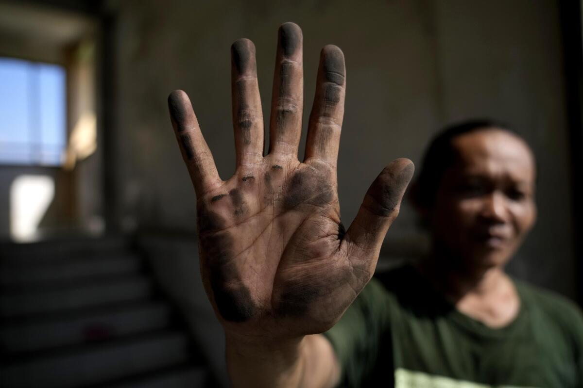 Cecep Supriyadi shows their dirty hand after touching a net installed to prevent dust particles.