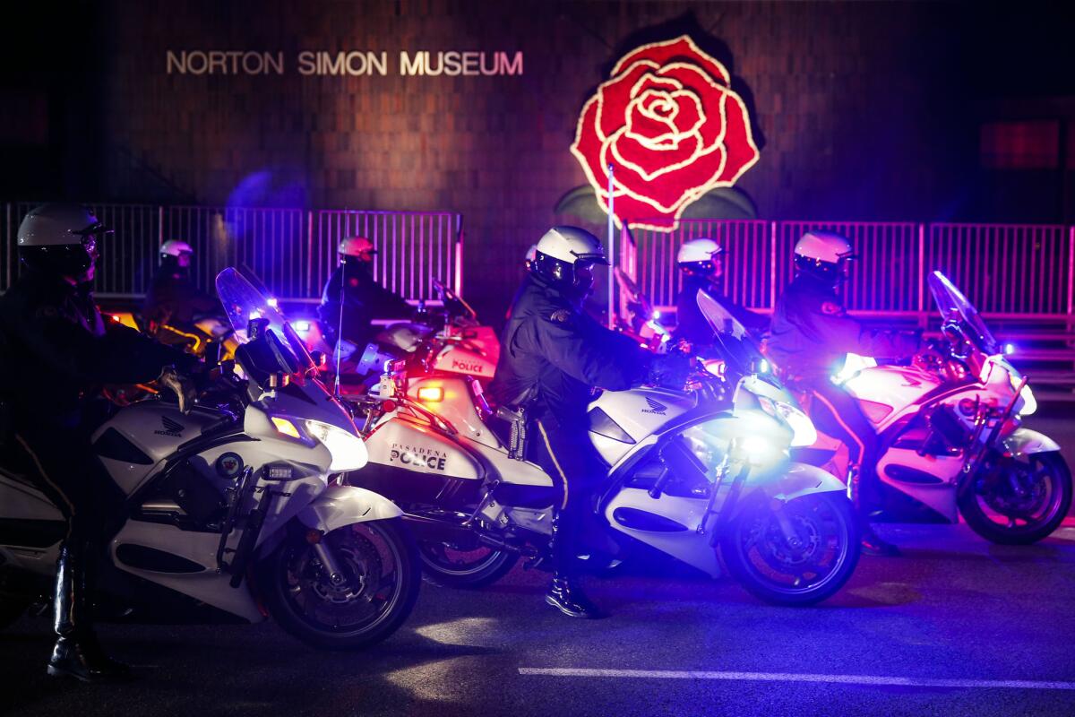 Pasadena motorcycle police officers get into formation in front of the Norton Simon Museum on Colorado Boulevard before the Rose Parade early Thursday morning. Eleven people were arrested at the Rose Parade overnight.