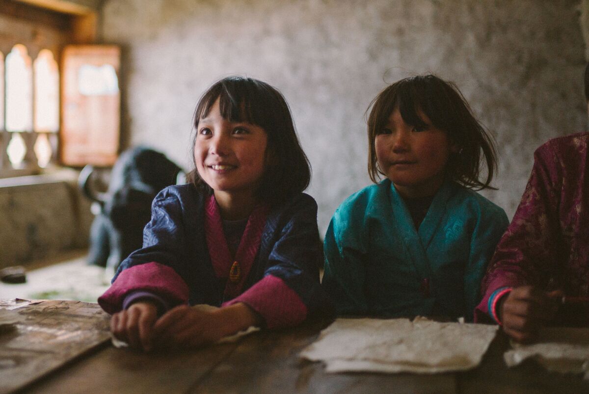 Two young girls wear colorful robes in the movie “Lunana: A Yak in the Classroom.” Photo courtesy of Samuel Goldwyn Films.