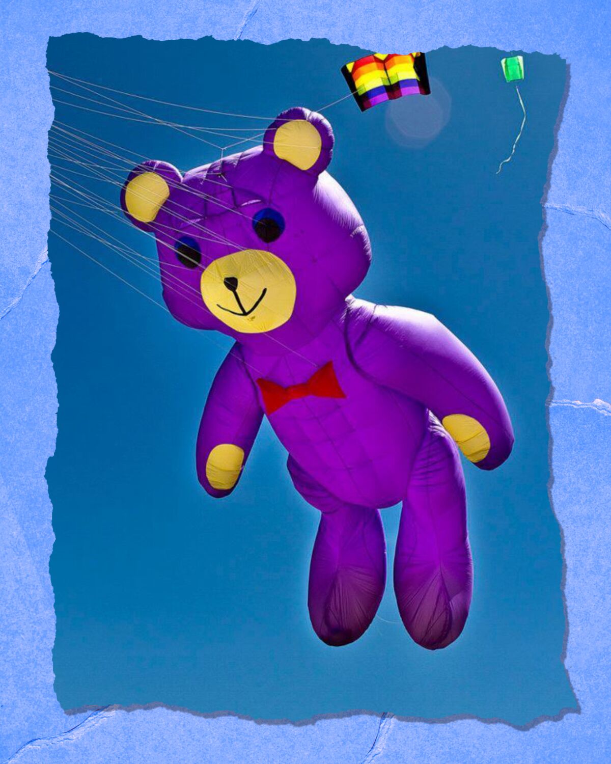 An inflated bear with a bowtie floats in the air.