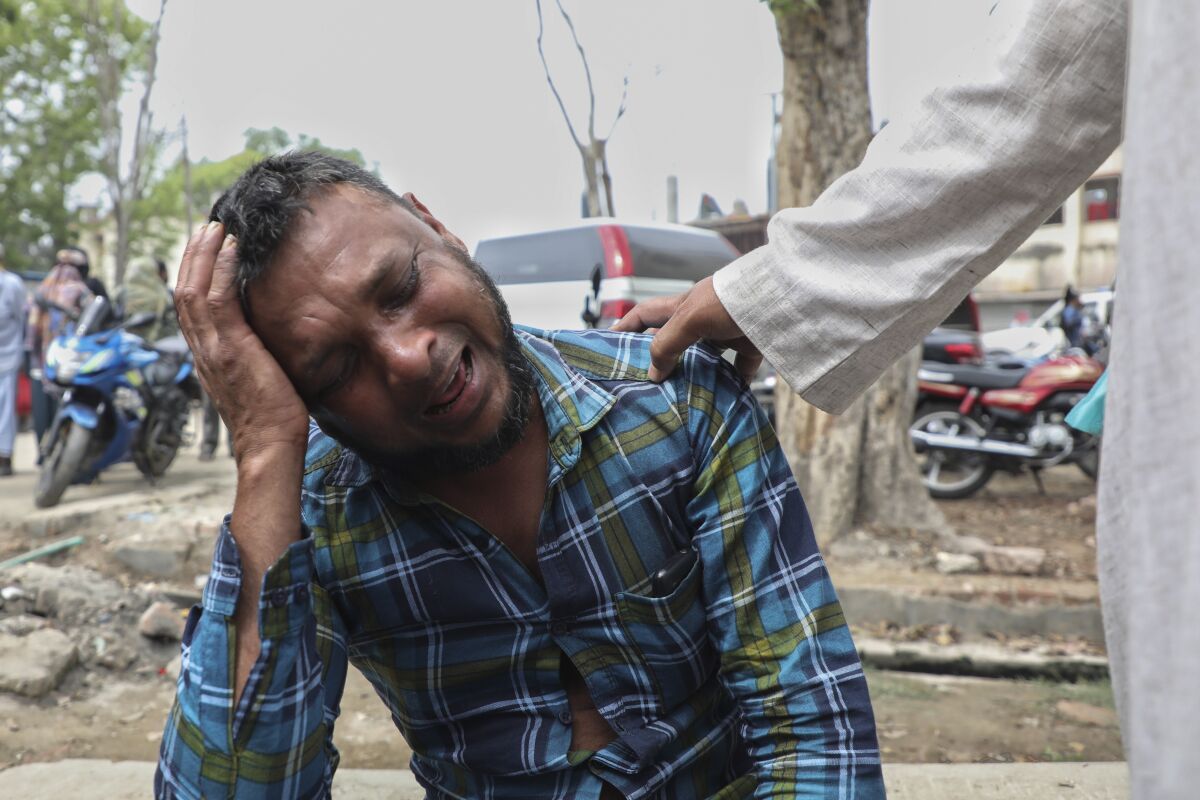 An unidentified man grieves as relatives receive bodies of victims of a road accident after a bus fell into a roadside ditch in Shibchar area in Madaripur district, Bangladesh, Sunday, March 19, 2023. More than a dozen people were killed and more were injured in the accident. (AP Photo/Jibon Ahmed)