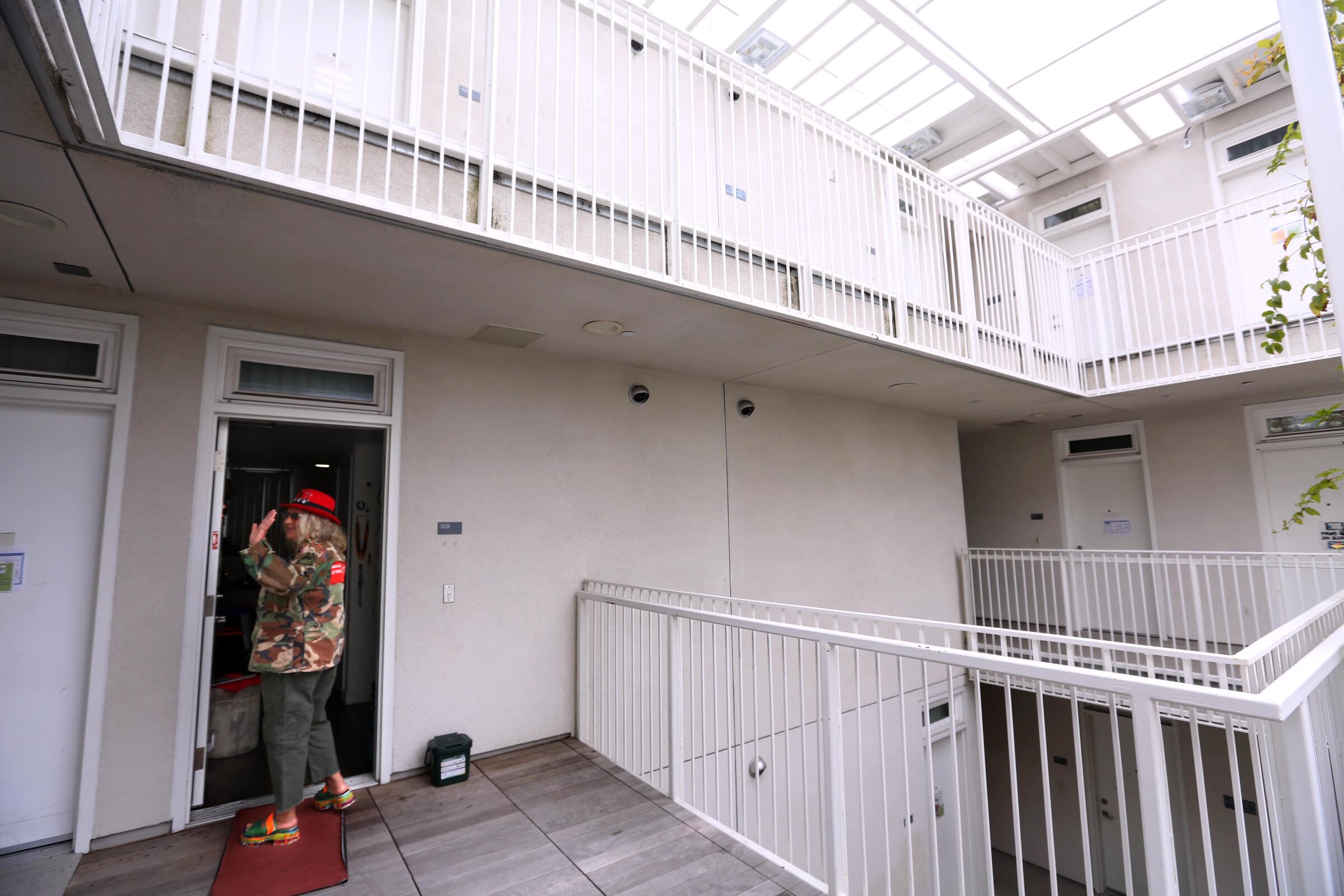 A woman stands outside her apartment