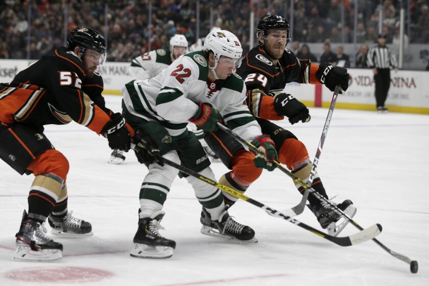 Minnesota Wild left wing Kevin Fiala, center, of Switzerland, gets between Anaheim Ducks defenseman Matt Irwin, left, and center Carter Rowney, right, in a battle for the puck during the first period of an NHL hockey game in Anaheim, Calif., Sunday, March 8, 2020. (AP Photo/Alex Gallardo)