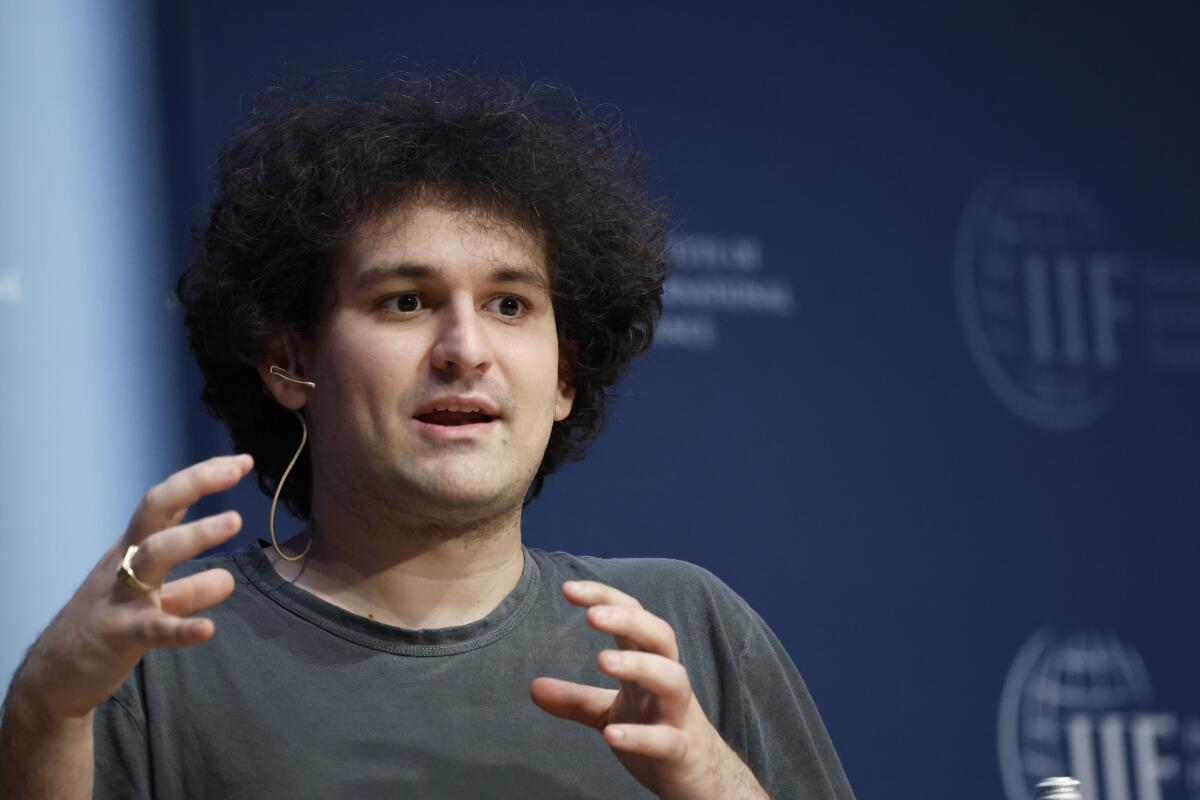 A man in a T-shirt with an earpiece gesturing and speaking 