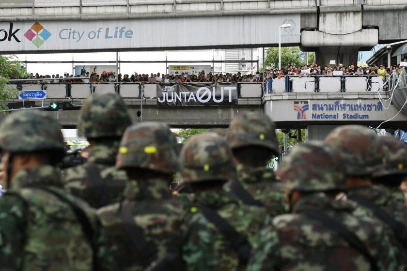 Thai soldiers stand guard as hundreds of pro-democracy activists protest the military coup in the center of Bangkok.