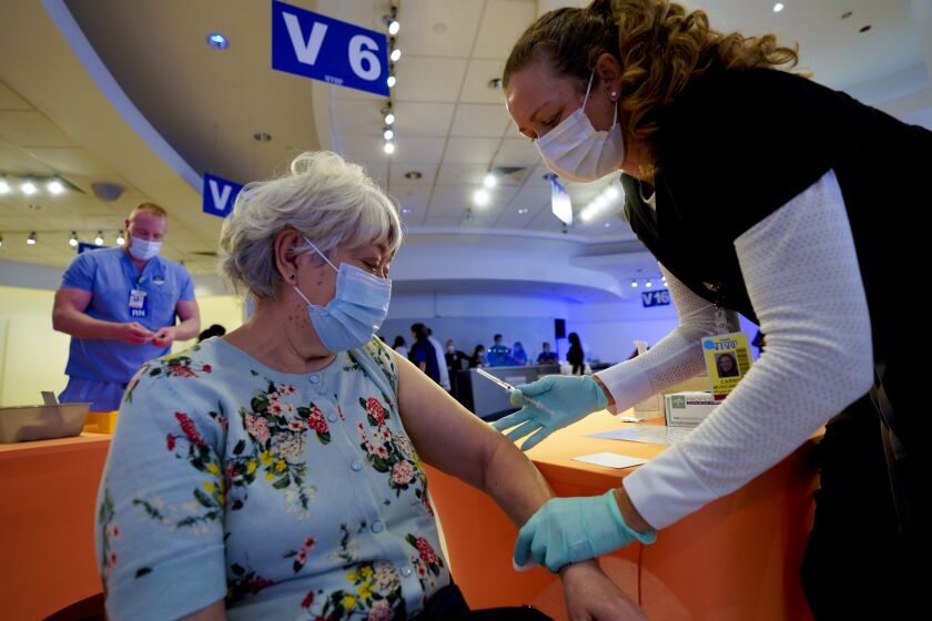 LA MESA, CA - FEBRUARY 02: Dualupe Rosette, 68 fro Spring Valley received her first dose of the COVID vaccine at Grossmont Center on Tuesday from Carrie Musicant, PA. Sharp HealthCare opened their latest COVID vaccine site at Grossmont Center in La Mesa on Tuesday, February 2, 2021. On their first day at the La Mesa site, officials report to have a scheduled a little more than 2000 vaccine appointments for Tuesday. (Nelvin C. Cepeda / The San Diego Union-Tribune)