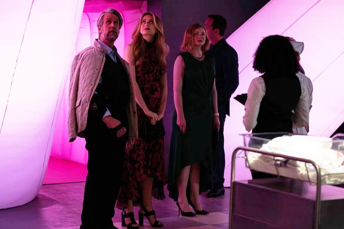 The siblings of "Succession" walk through a tunnel wrapped in pink lights.