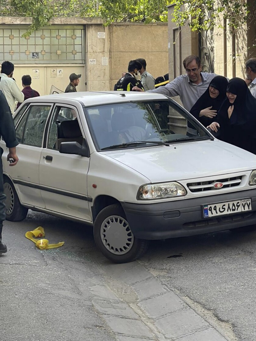 Family members weep next to a car where a Revolutionary Guard colonel was shot.