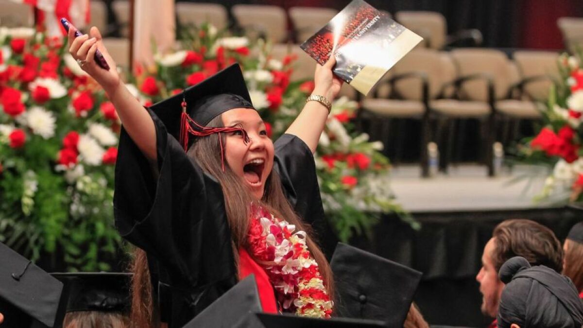 Noelle Green waves to family and friends before College of Arts and Letters graduation at SDSU