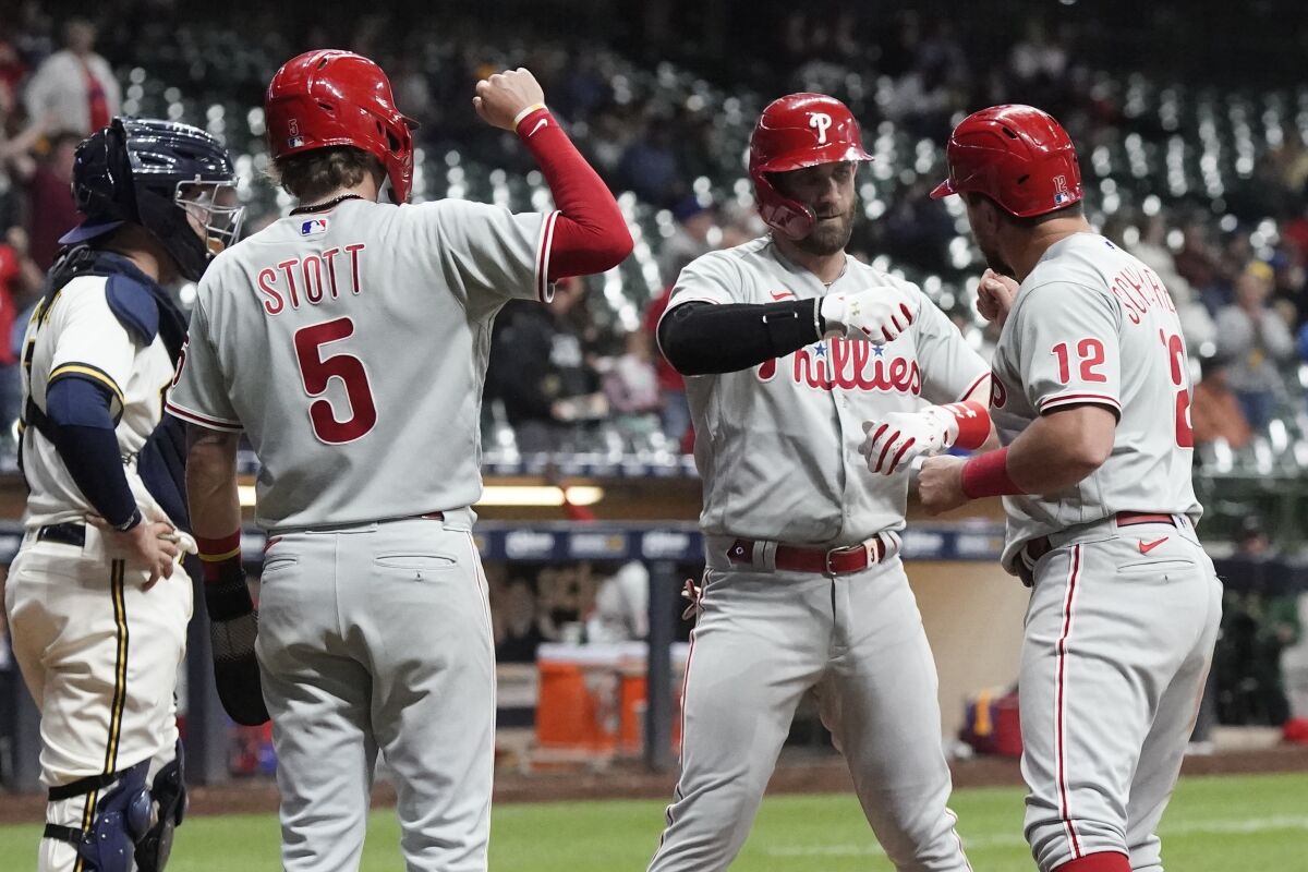 Philadelphia Phillies' Bryce Harper is congratulated by Kyle Schwarber (12) and Bryson Stott (5) after hitting a three-run home run during the ninth inning of a baseball game against the Milwaukee Brewers Wednesday, June 8, 2022, in Milwaukee. (AP Photo/Morry Gash)