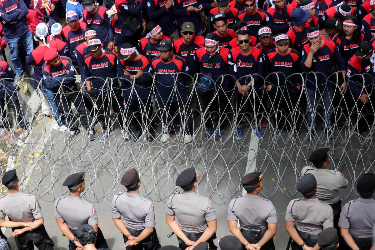 Police officers stand in formation facing Indonesian workers take part in a protest march to the Presidential Palace during a 'May Day' rally in Jakarta. (BAGUS INDAHONO/EPA/REX/Shutterstock)