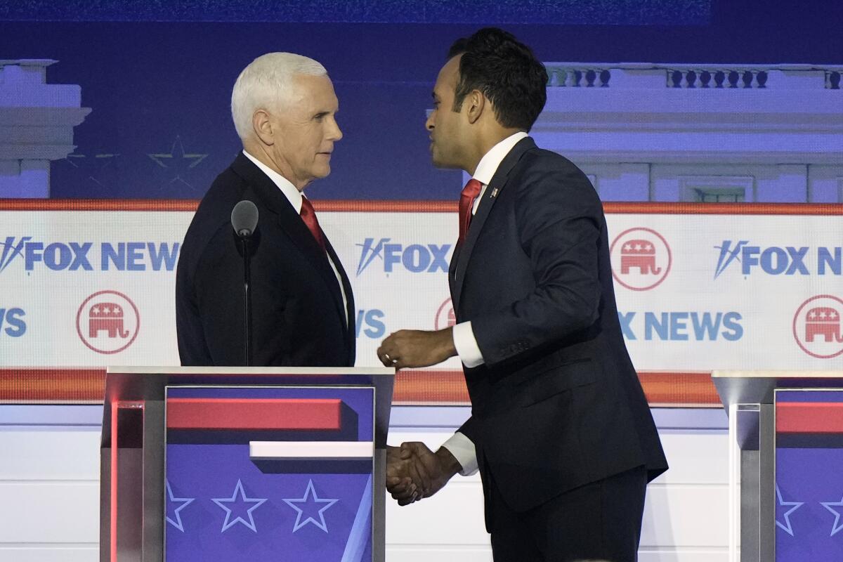 Two men shake hands on red, white and blue debate stage 