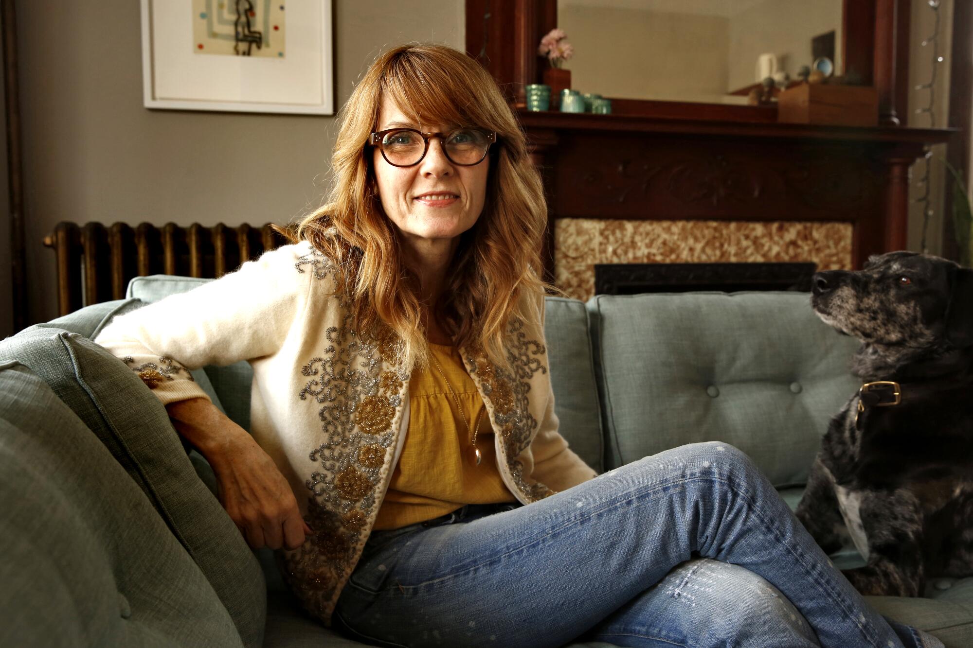 A woman, author Elizabeth Crane, seated on a couch.