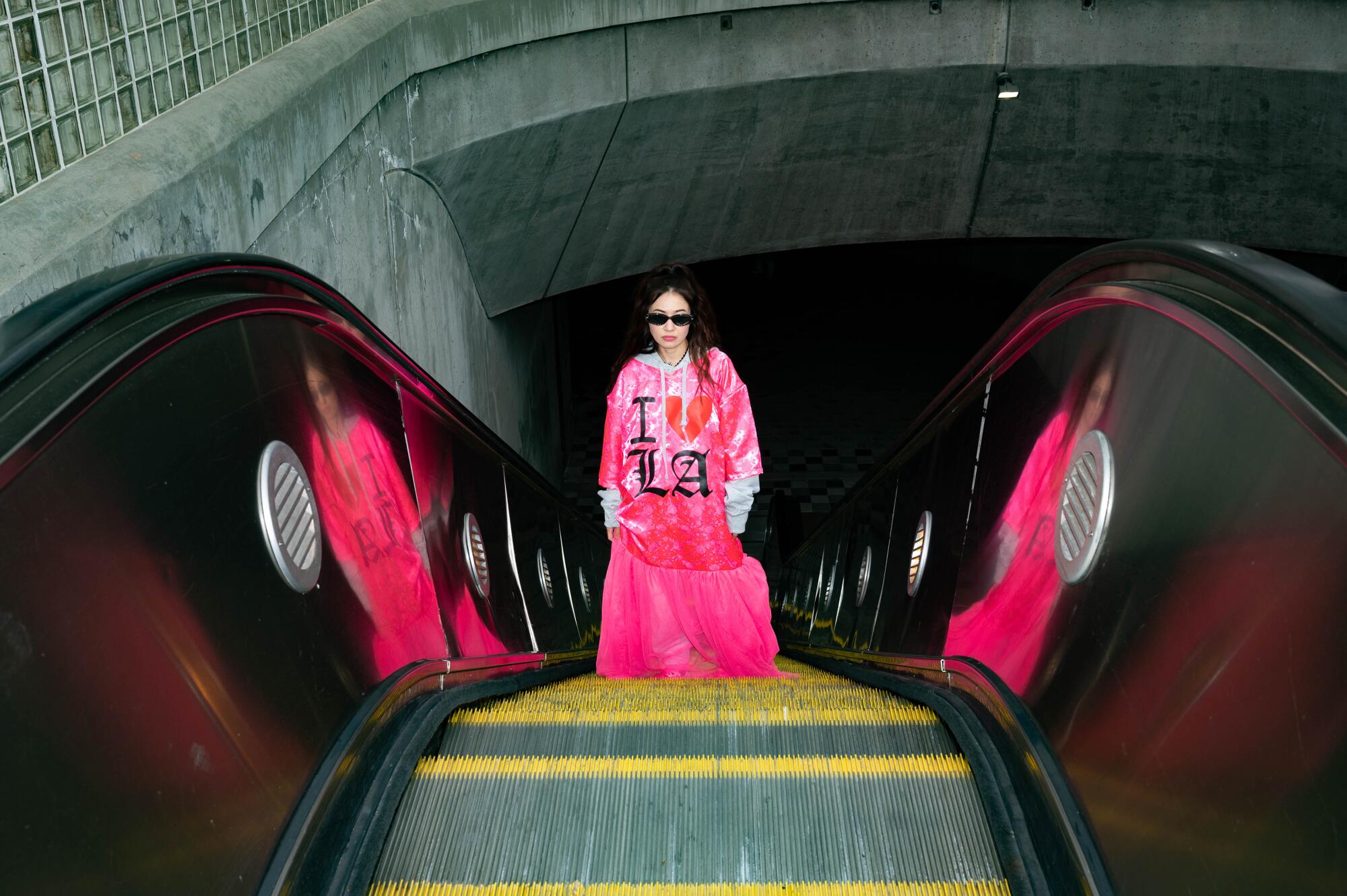 A model in a hot-pink outfit, reflected on either side so there appear to be three of her