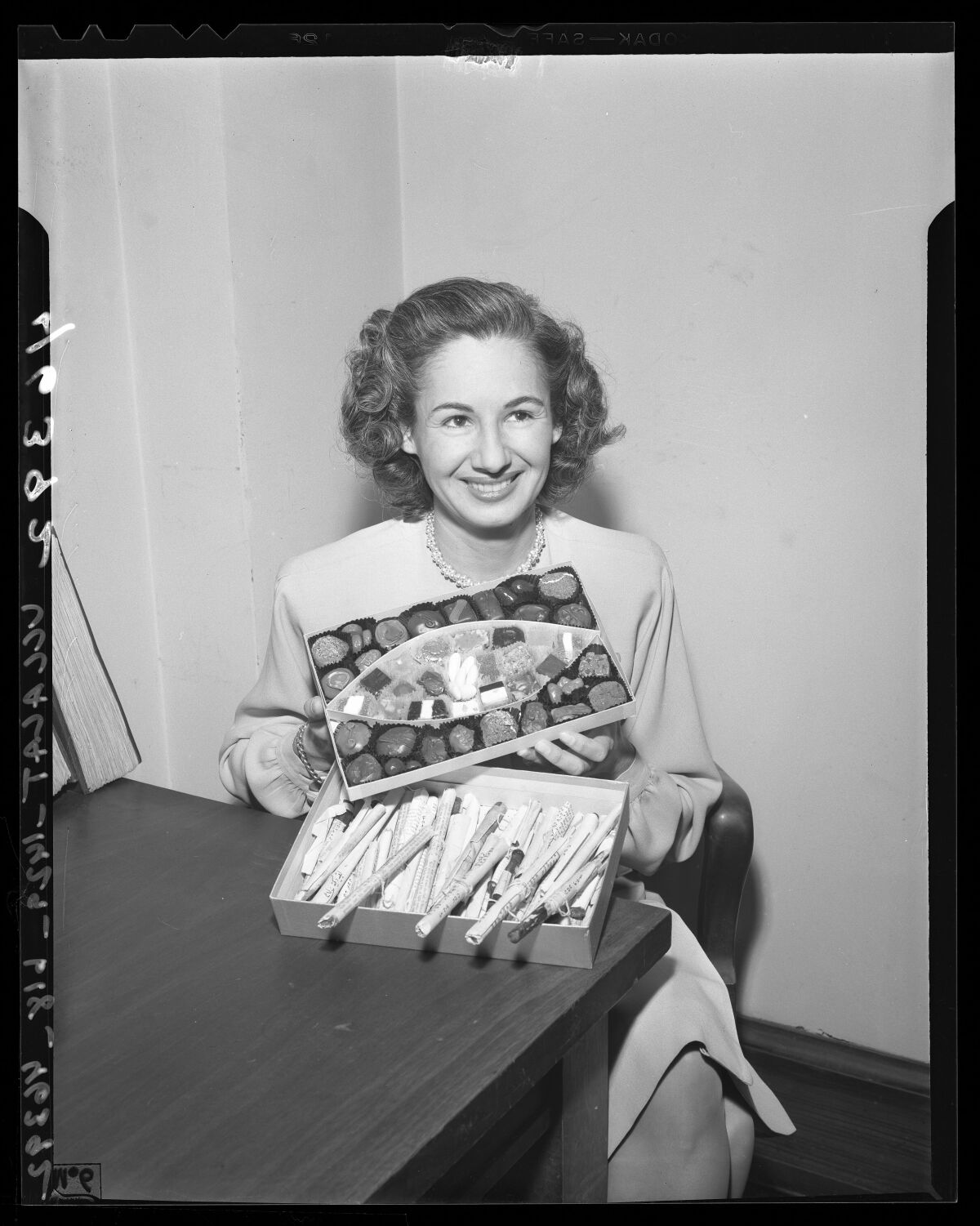 A 1940s woman smiles and holds a tray of candy to reveal opium underneath.
