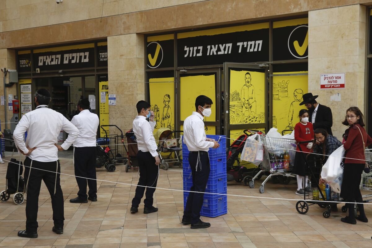 Ultra-Orthodox Jews wait to enter a supermarket while keeping a safe social distance as part of the Israeli government's measures to stop the coronavirus.