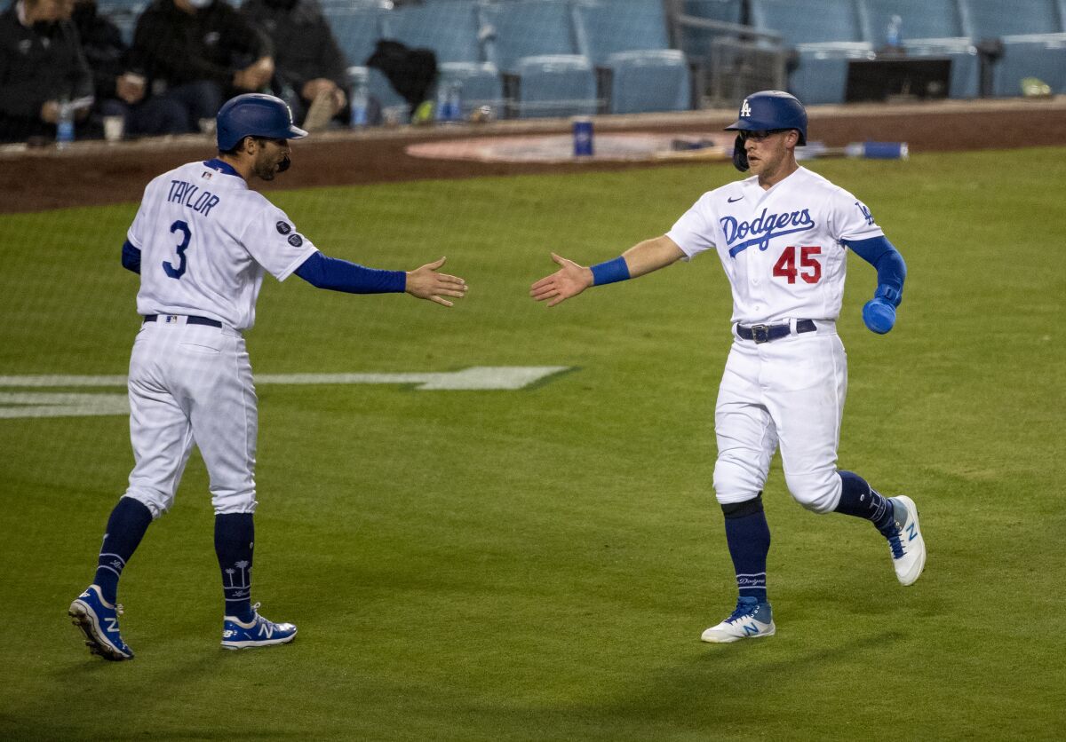 Chris Taylor and Corey Seager reach out a hand to each other on the field.