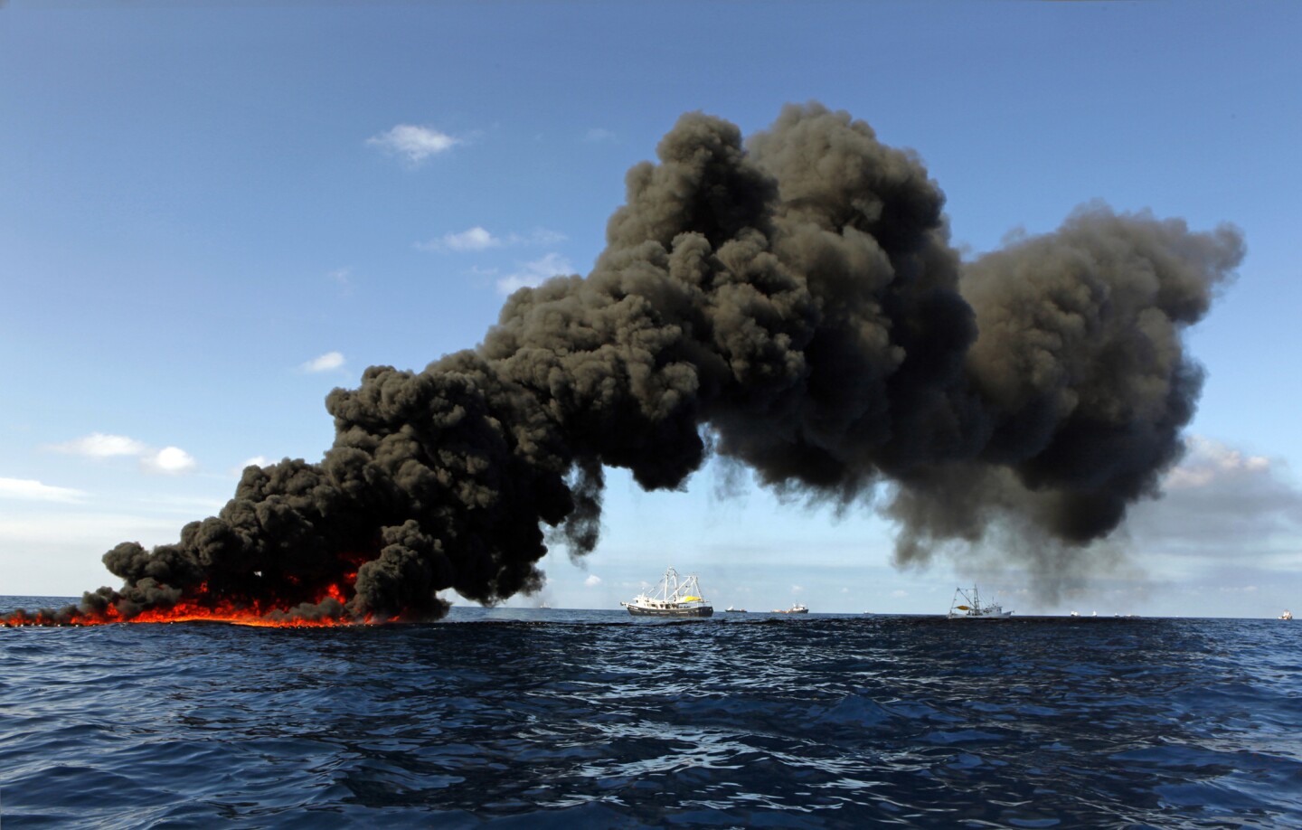 Boats skim oil and then ignite it on the surface north of the spill site.