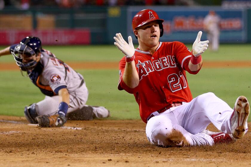 Angels center fielder Mike Trout celebrates as he slides safely past Astros catcher Jason Castro in the fourth inning Friday night in Anaheim.