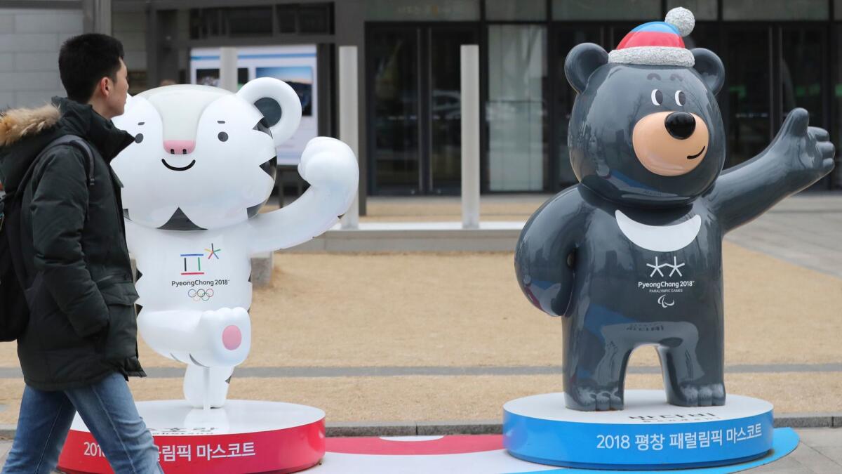 A man passes by official mascots of the 2018 Pyeongchang Winter Games, white tiger Soohorang for the Olympics, and Asiatic black bear Bandabi for the Paralympics, in downtown Seoul on Monday.
