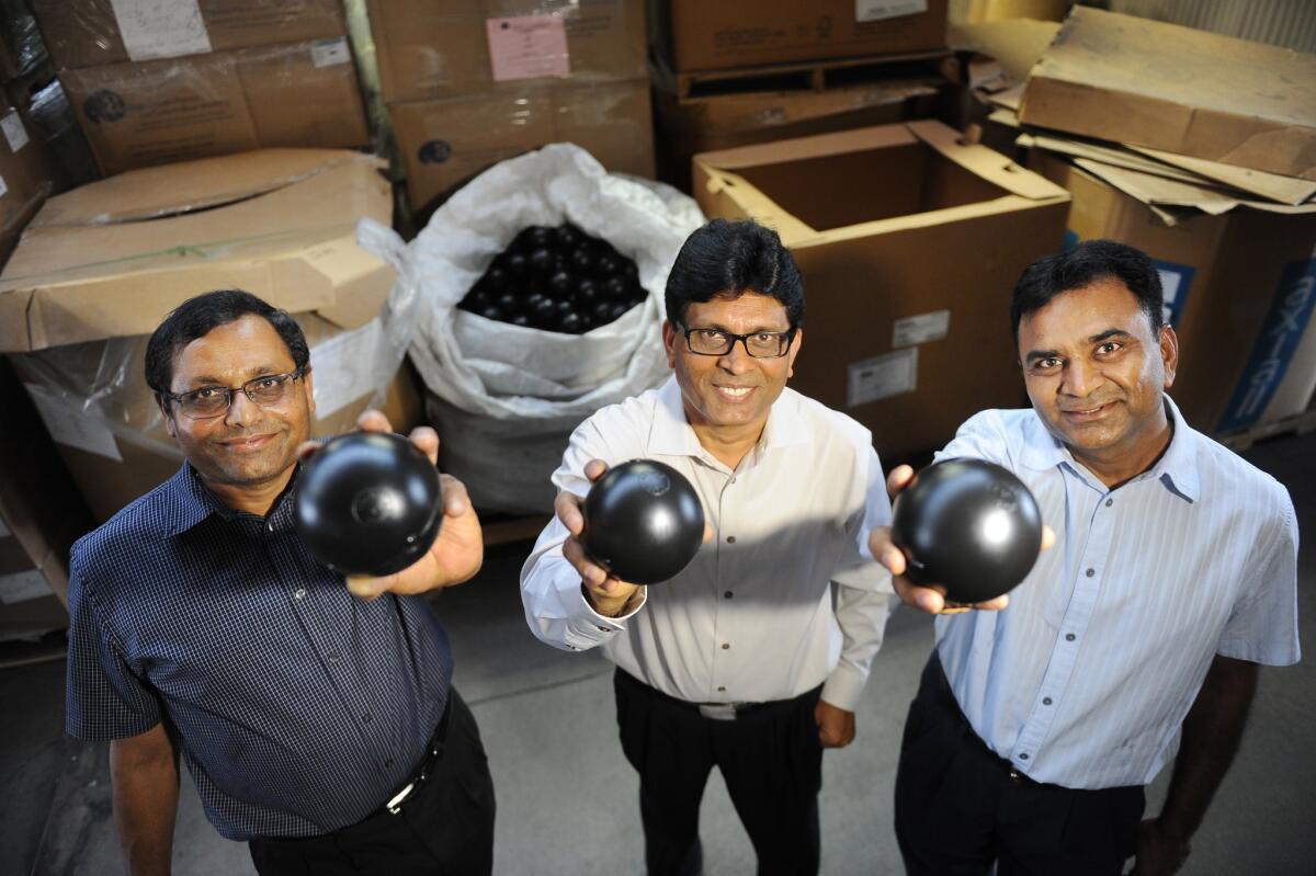 Business partners C.P. Kheni, left, Vasant Dobaria and Praful Bajaria of Artisan Screen Printing hold some of the 89.6 million black plastic shade balls manufactured at their plant in Azusa.