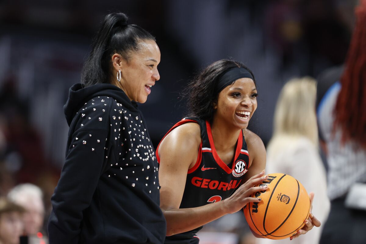 FILE - South Carolina head coach Dawn Staley, left, laughs with Georgia guard Diamond Battles during the second half of an NCAA college basketball game in Columbia, S.C., Sunday, Feb. 26, 2023. South Carolina is keenly aware that everyone remaining in the women's NCAA Tournament field is coming after the undefeated Gamecocks — and hard. “We're just about basketball,” coach Staley says with admiration. “We really are.” (AP Photo/Nell Redmond, File)
